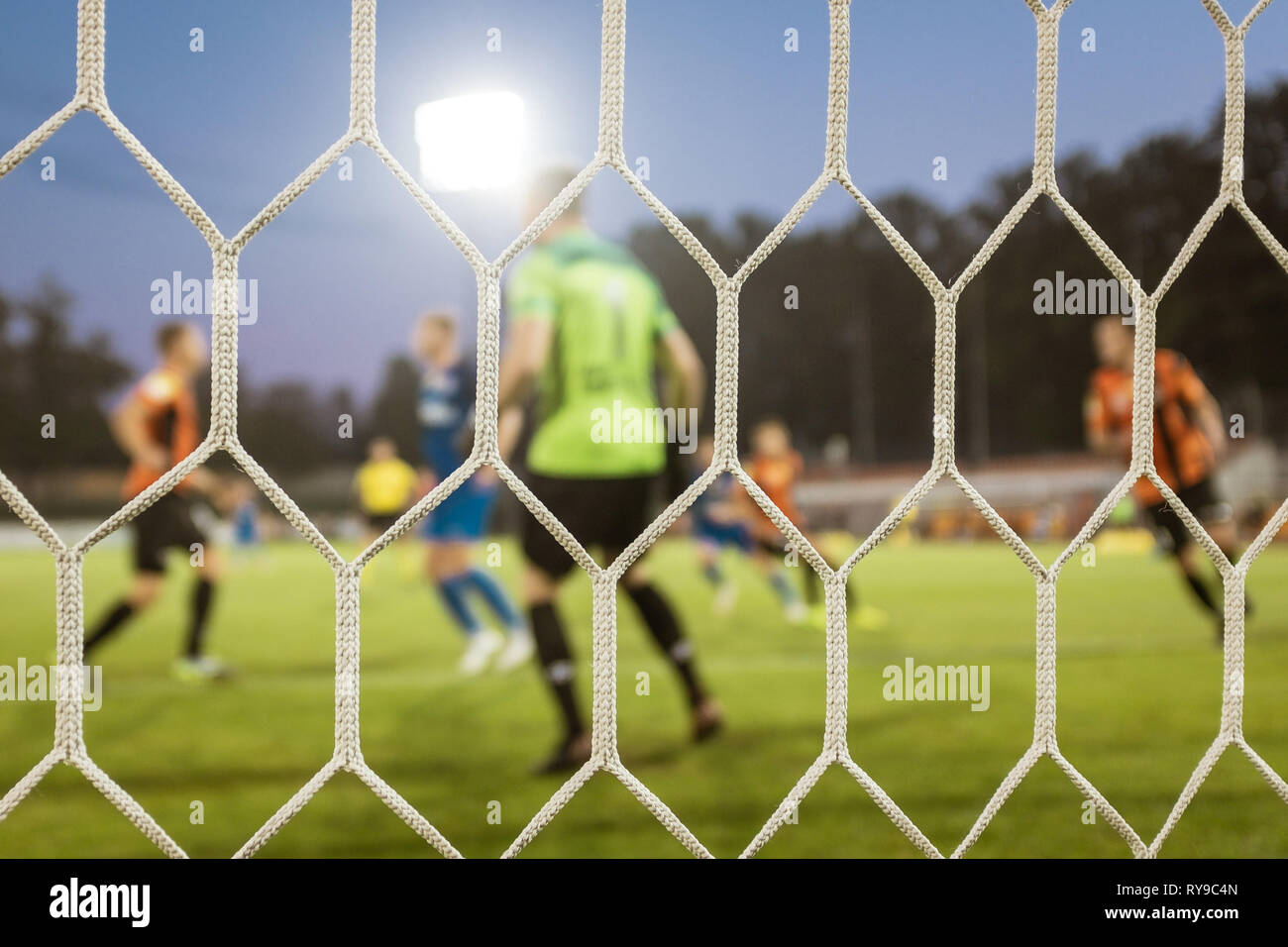 Net in einem Fußballtor mit playrs und Tonhöhe im Hintergrund. Stockfoto