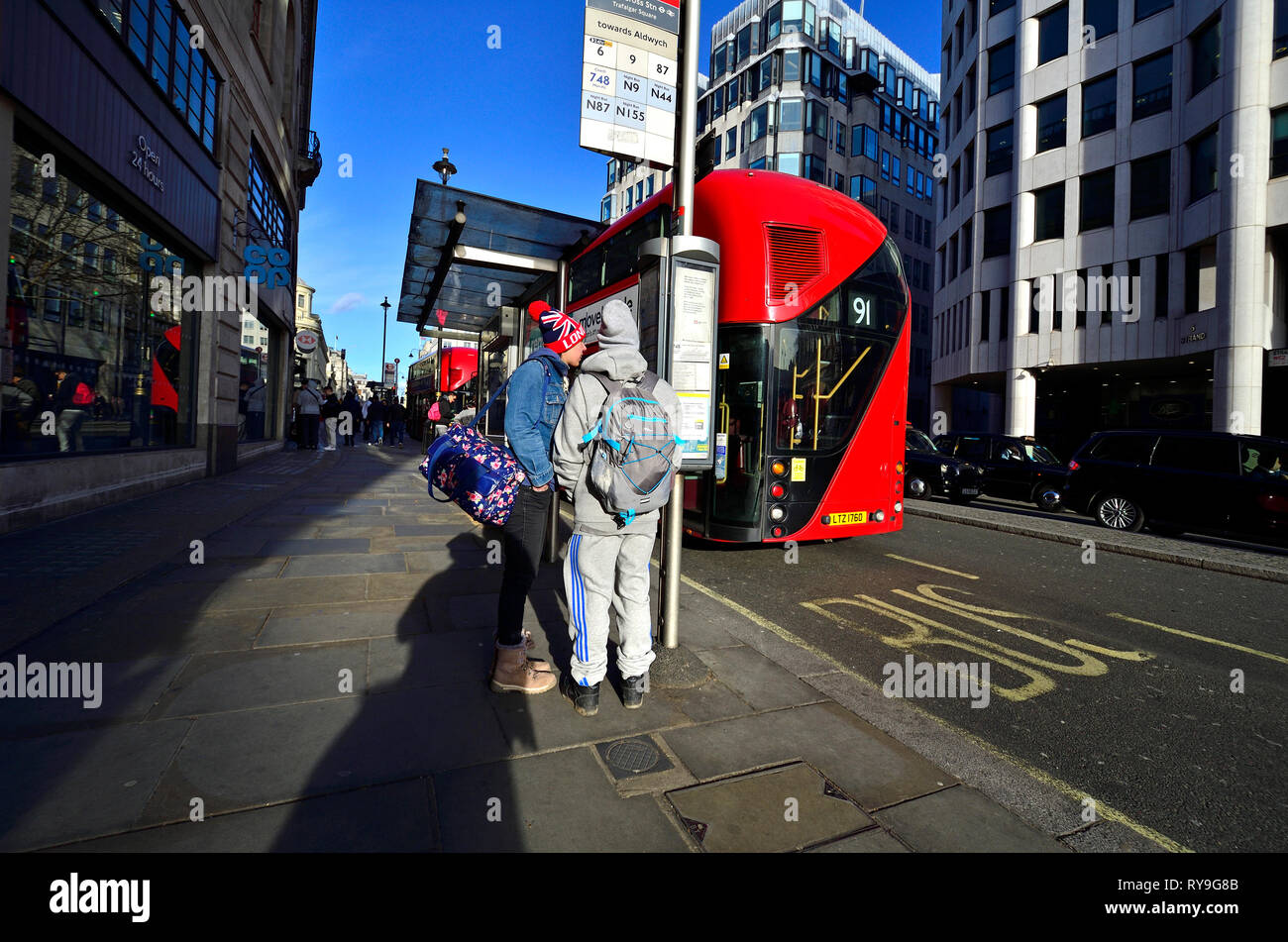 London, England, UK. Zwei Personen an einer Bushaltestelle in die Litze Stockfoto