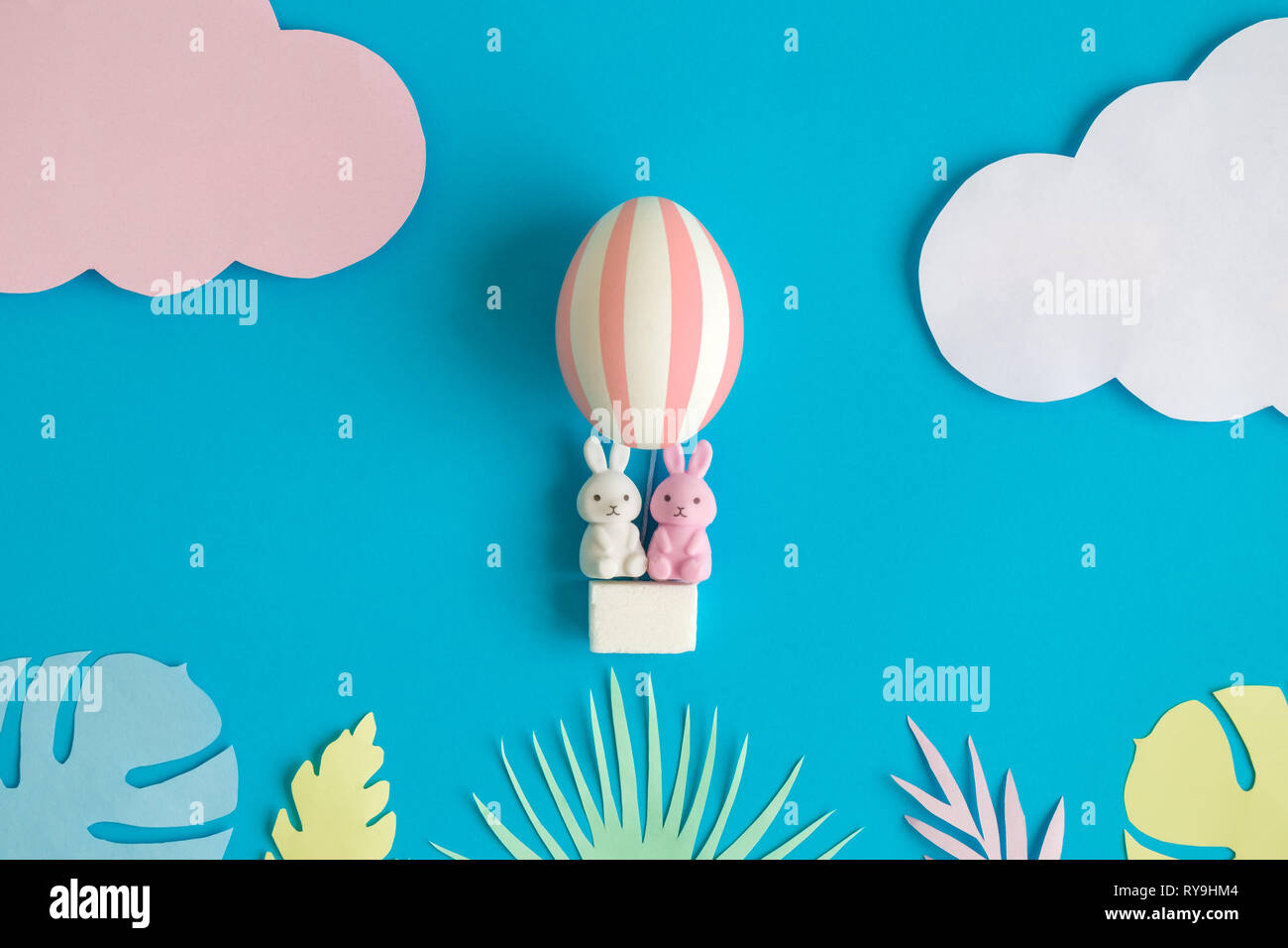 Kaninchen in Osterei Heißluftballon mit bunten tropischen Blättern minimal Kreativurlaub Konzept. Stockfoto