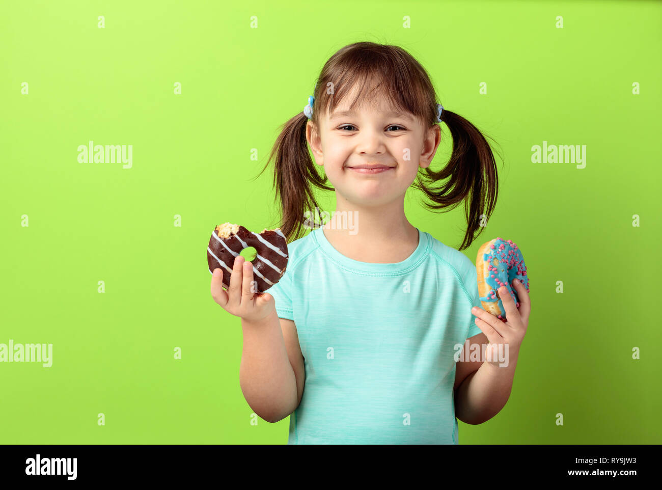 Glückliches Mädchen in einem türkis-t-shirt mit Donuts. Grüner Hintergrund. Kopieren Sie Platz. Stockfoto