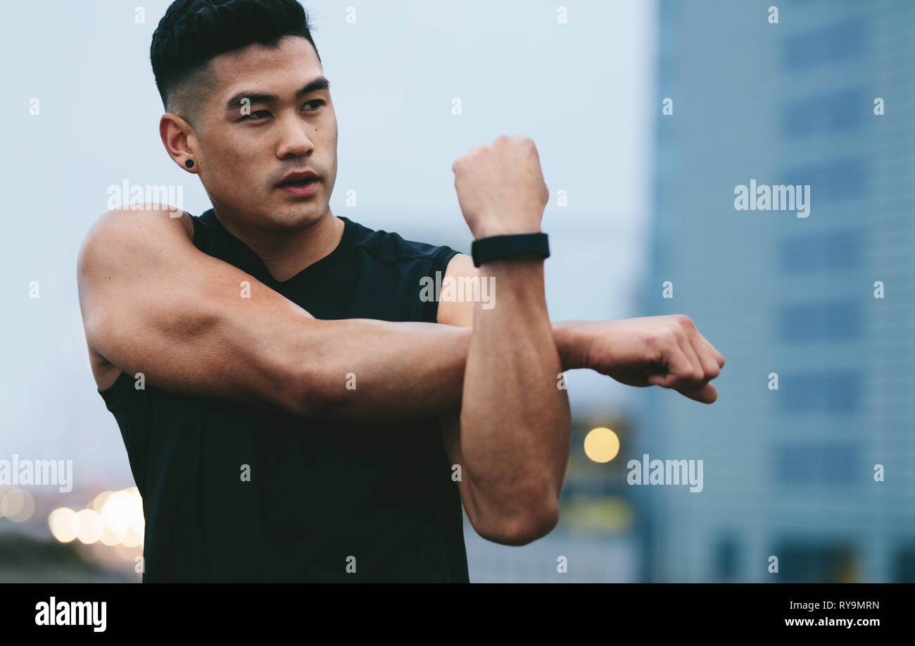 Passen junge Mann, muskulös, außerhalb stretching Hände und weg schauen. Asiatische fitness Modell tun warmup Workout. Stockfoto