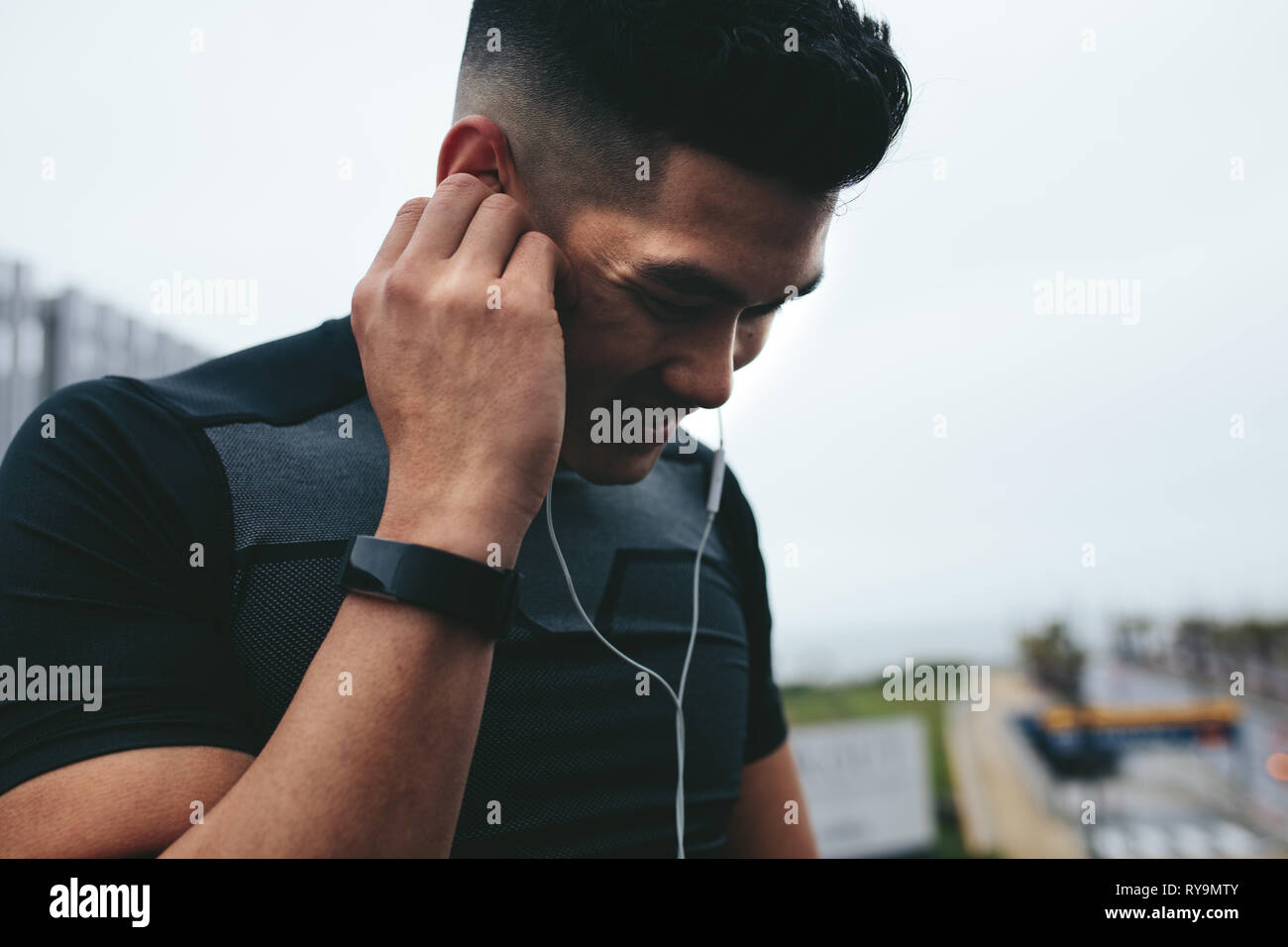 Nahaufnahme von jungen asiatischen Mann in Sportkleidung tragen Kopfhörer Musik hören während outdoor training. Stockfoto