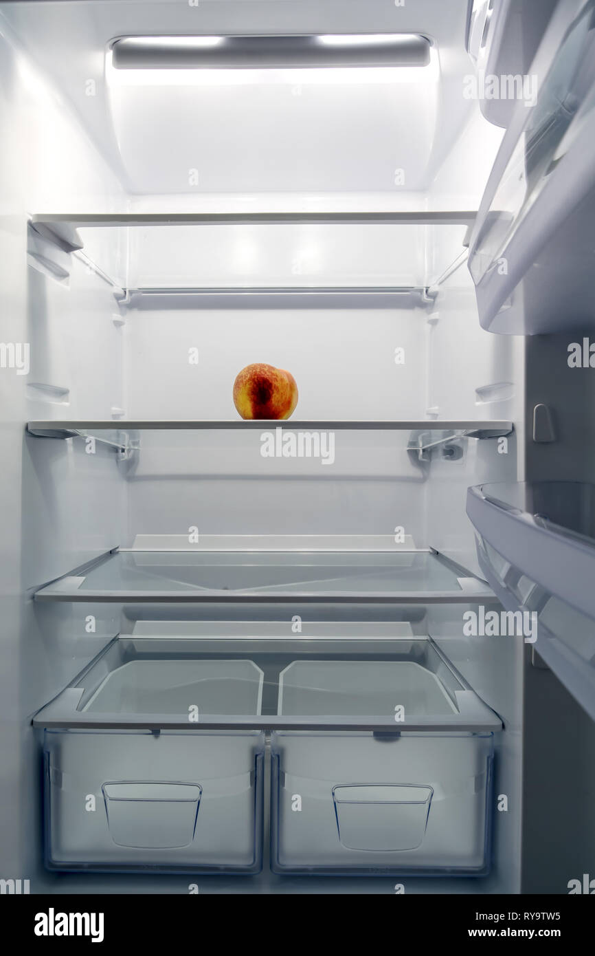 Einen großen weißen Kühlschrank ist fast leer, nur ein Pfirsich ist in ihm.  Es ist dringend erforderlich, Lebensmittel zu kaufen Stockfotografie - Alamy