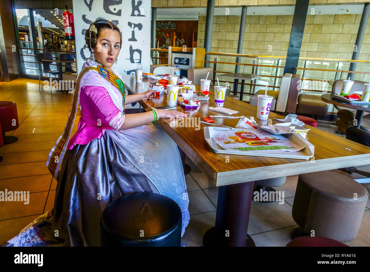 Las Fallas Festival, Valencia, Fallera Mädchen in traditioneller Tracht Essen in Spanien McDonalds Stockfoto