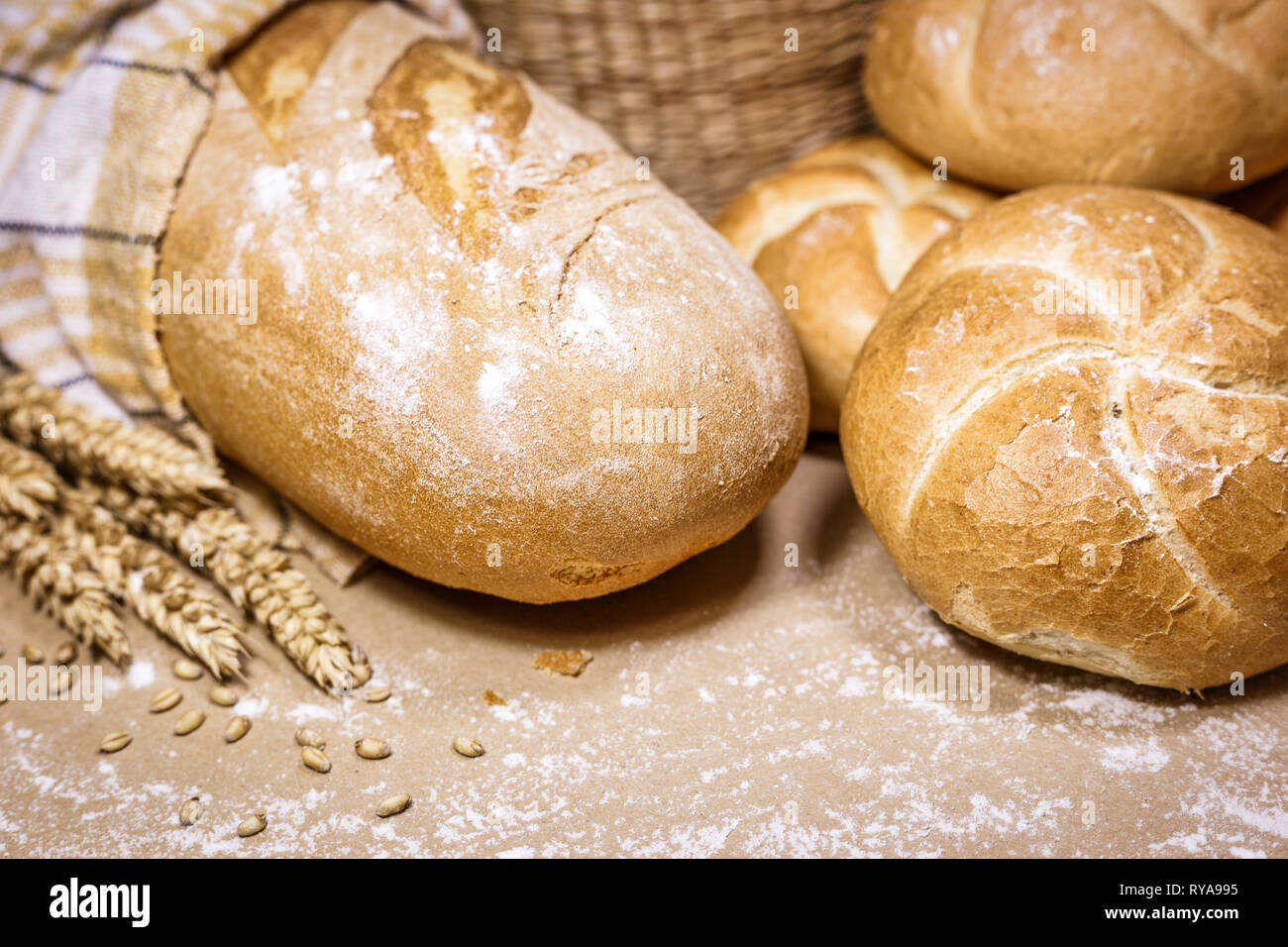 Nahaufnahme der frisch gebackene Brot auf einem urigen Hintergrund mit Weizen und Mehl. Eine Bäckerei und ein Lebensmittelgeschäft. Stockfoto