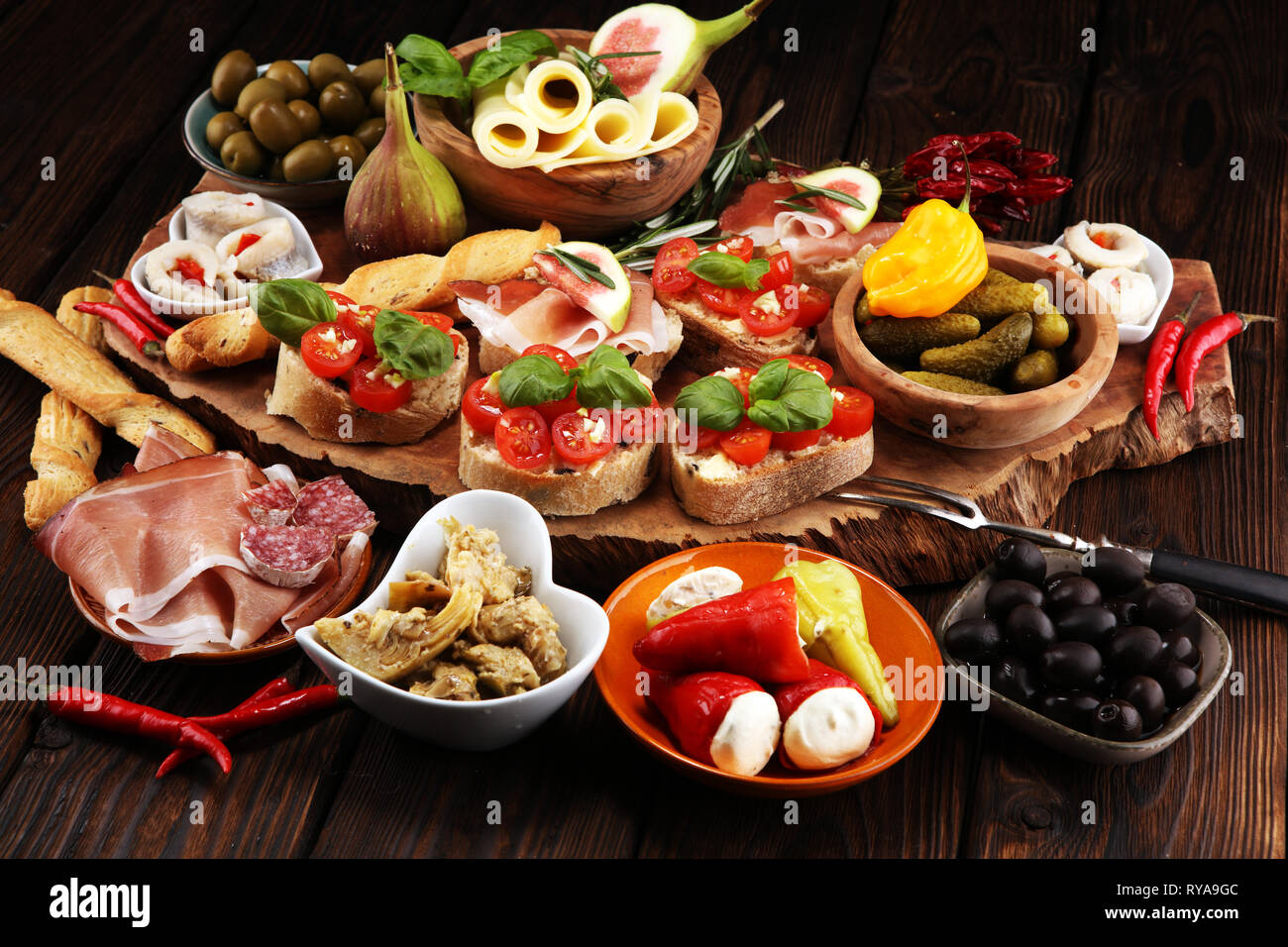 Italienische Antipasti Wein Snacks. Käsesorte, mediterrane Oliven, Gurken, Prosciutto di Parma, Tomaten, Artischocken auf dem Tisch Stockfoto