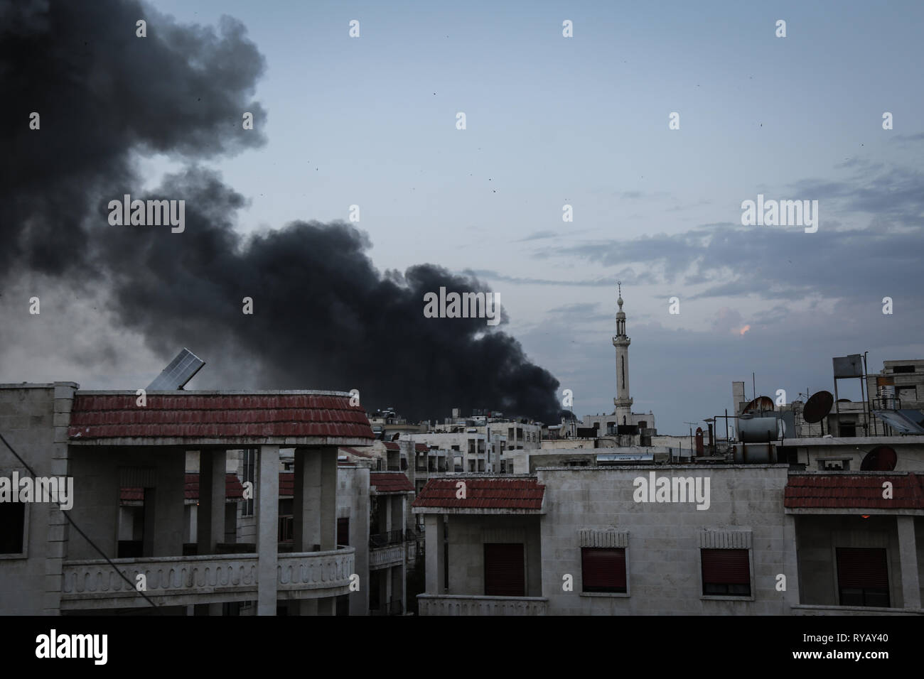 Idlib, Syrien. 13 Mär, 2019. Dichter Rauch steigt von Gebäuden nach Luftangriffen, die glaubten, durch russische Kampfflugzeuge auf Wohngebiete in der Innenstadt von Idlib montiert werden. Die syrischen Weiße Helme freiwillige Rettung Gruppe, die nur in den von den Rebellen besetzten Gebieten arbeitet, sagte, starben zwei Frauen und 19 andere wurden in die Streiks verletzt. Credit: Anas Alkharboutli/dpa/Alamy leben Nachrichten Stockfoto