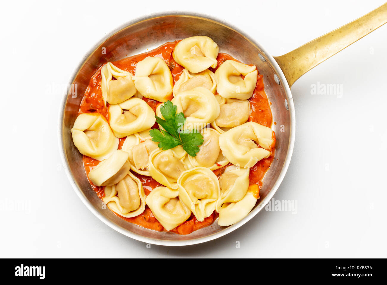 Tortellini auf Weiß mit Tomatensauce. Stockfoto