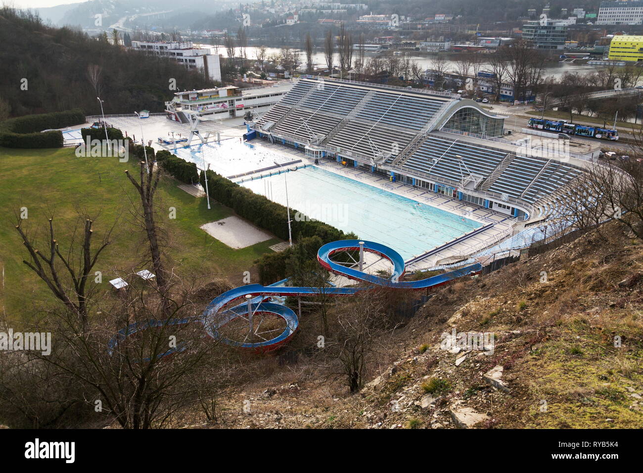 Größte Badelandschaft mit Innen- und Außenpools, Rodeln Wasserrutsche und tauchen Türme mit Moldau im Hintergrund, Podoli, Prag, Tschechische Stockfoto