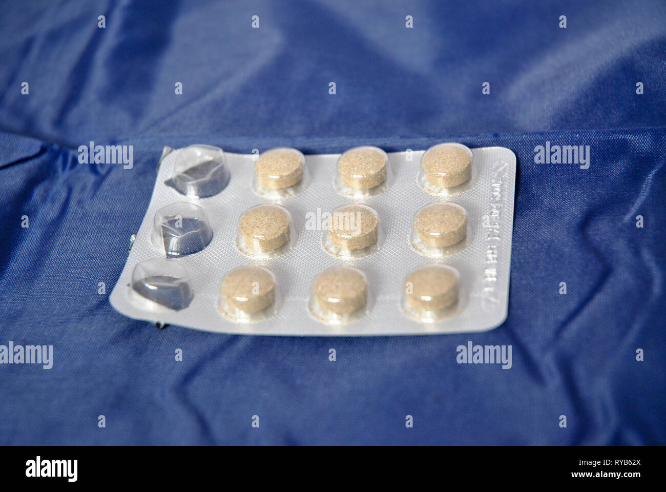 Eine Pille Blister mit 3 Tabletten vor einem blauen Hintergrund fehlt Stockfoto