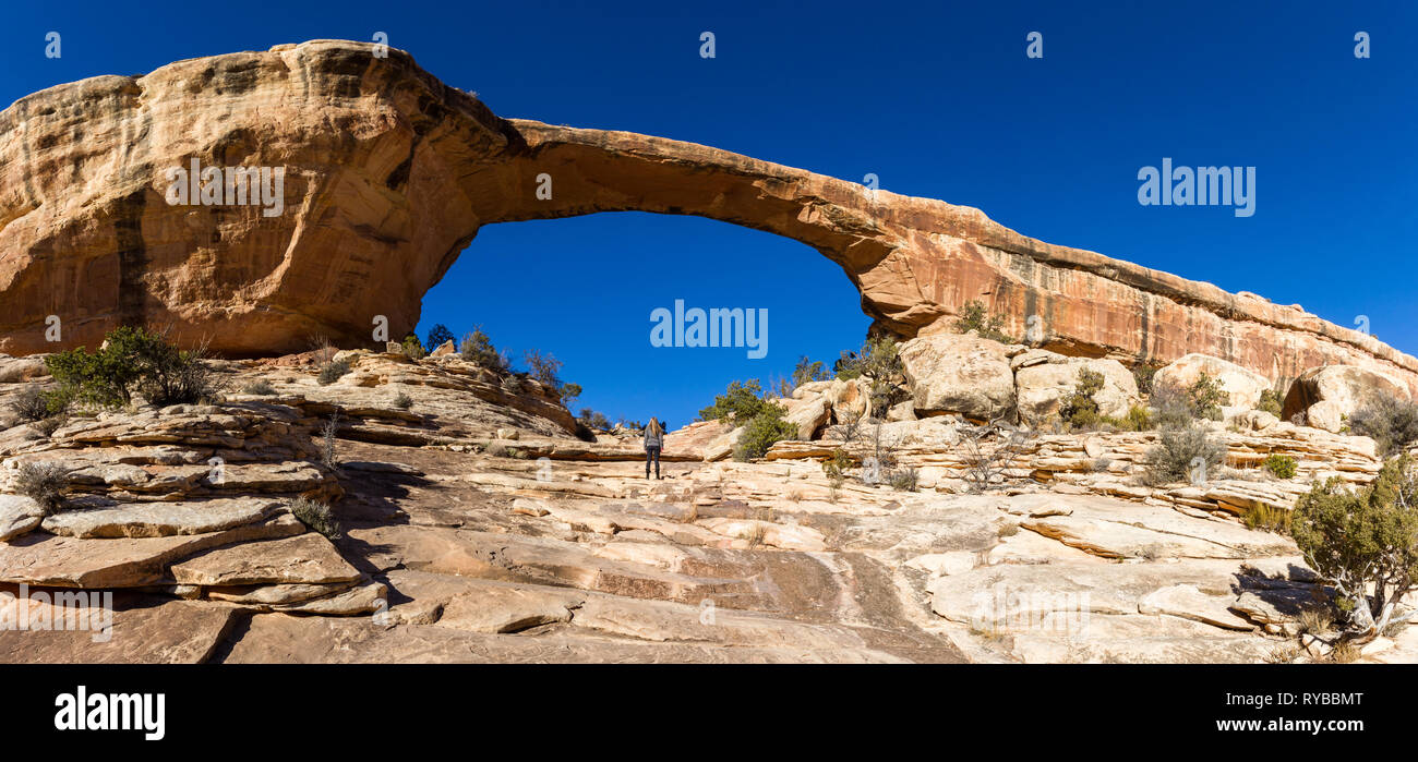 Weibliche Wanderer stehen an der Basis des Owachomo Bridge mit blauen Himmel im Hintergrund Stockfoto