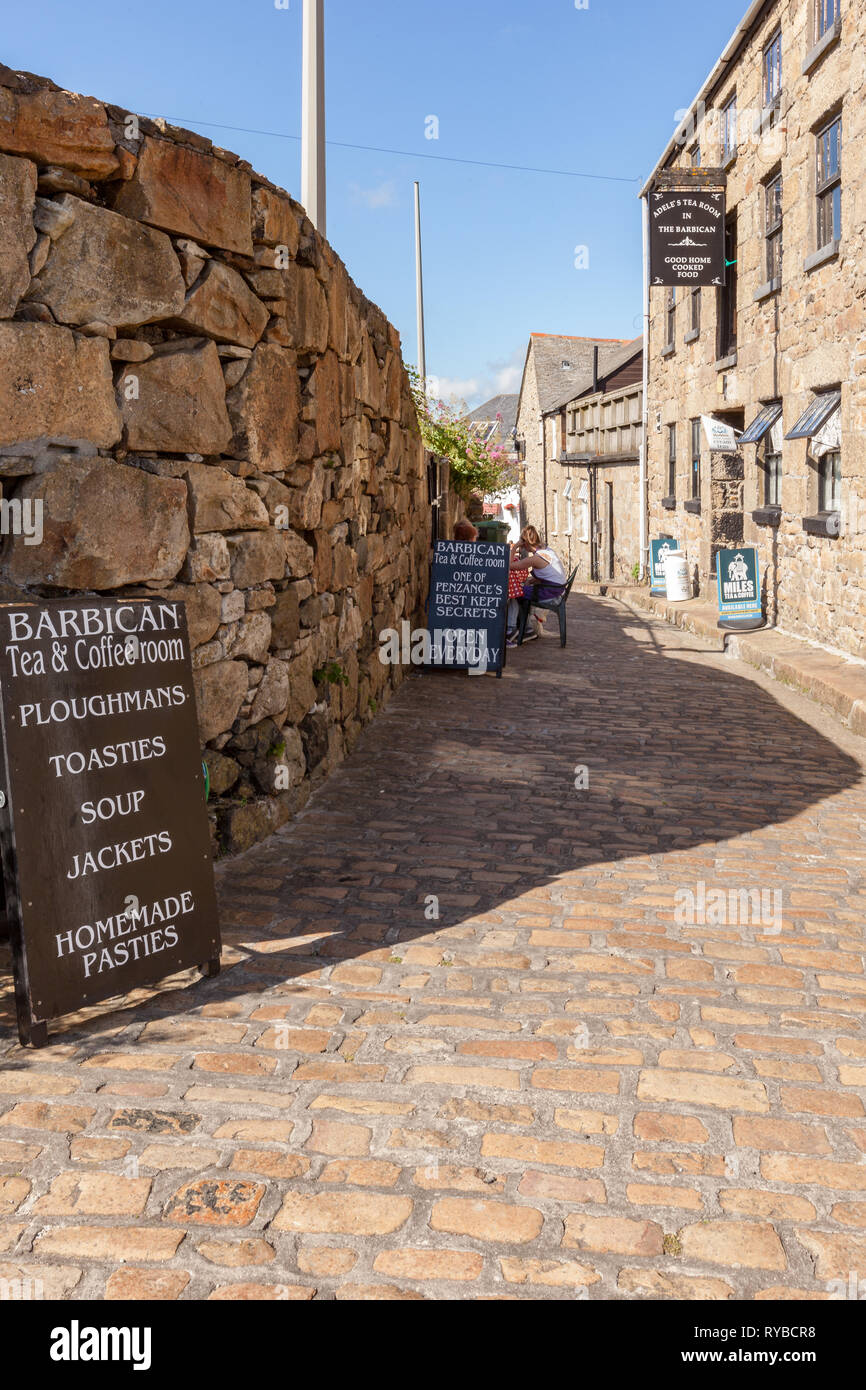 Blick von außen auf ein Cafe auf einer gepflasterten, Fußgänger-Lane in Penzance, Cornwall. Mit warmen, hellen, sonnigen Sommertag. Tafeln und Schilder. Stockfoto