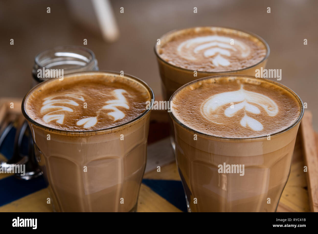 Drei Cappuccino im Glas serviert mit Mustern in den Schaum ...