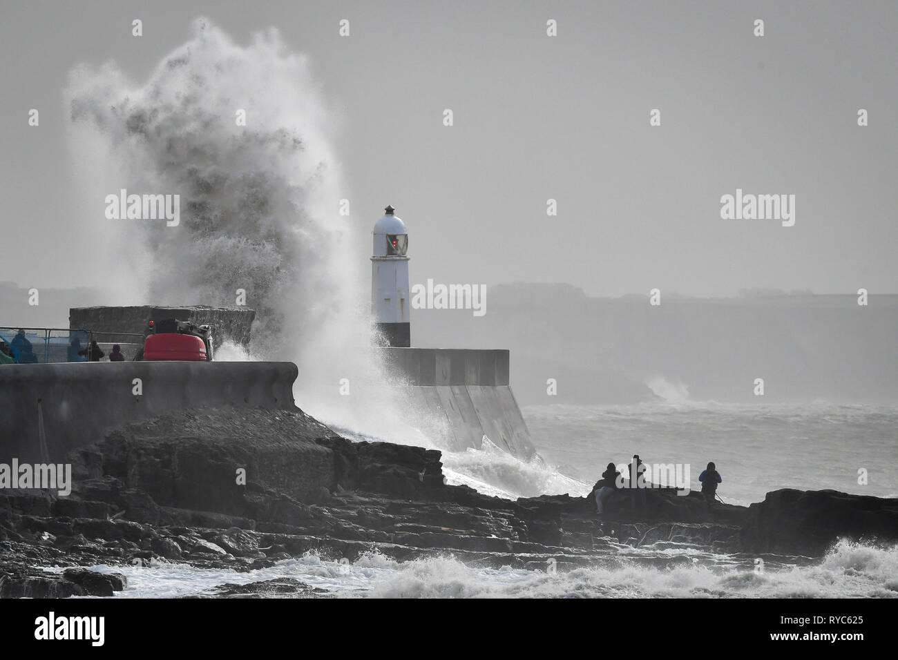 Riesige Wellen schlagen gegen die hafenmauer als Zuschauer von den Felsen aus sehen Sie in das Meer bei Porthcawl, Wales, in dem starke Regenfälle und starke Winde verursacht haben Reisen Störungen in einigen Teilen des Vereinigten Königreichs als Sturm Gareth Osten bewegt. Stockfoto