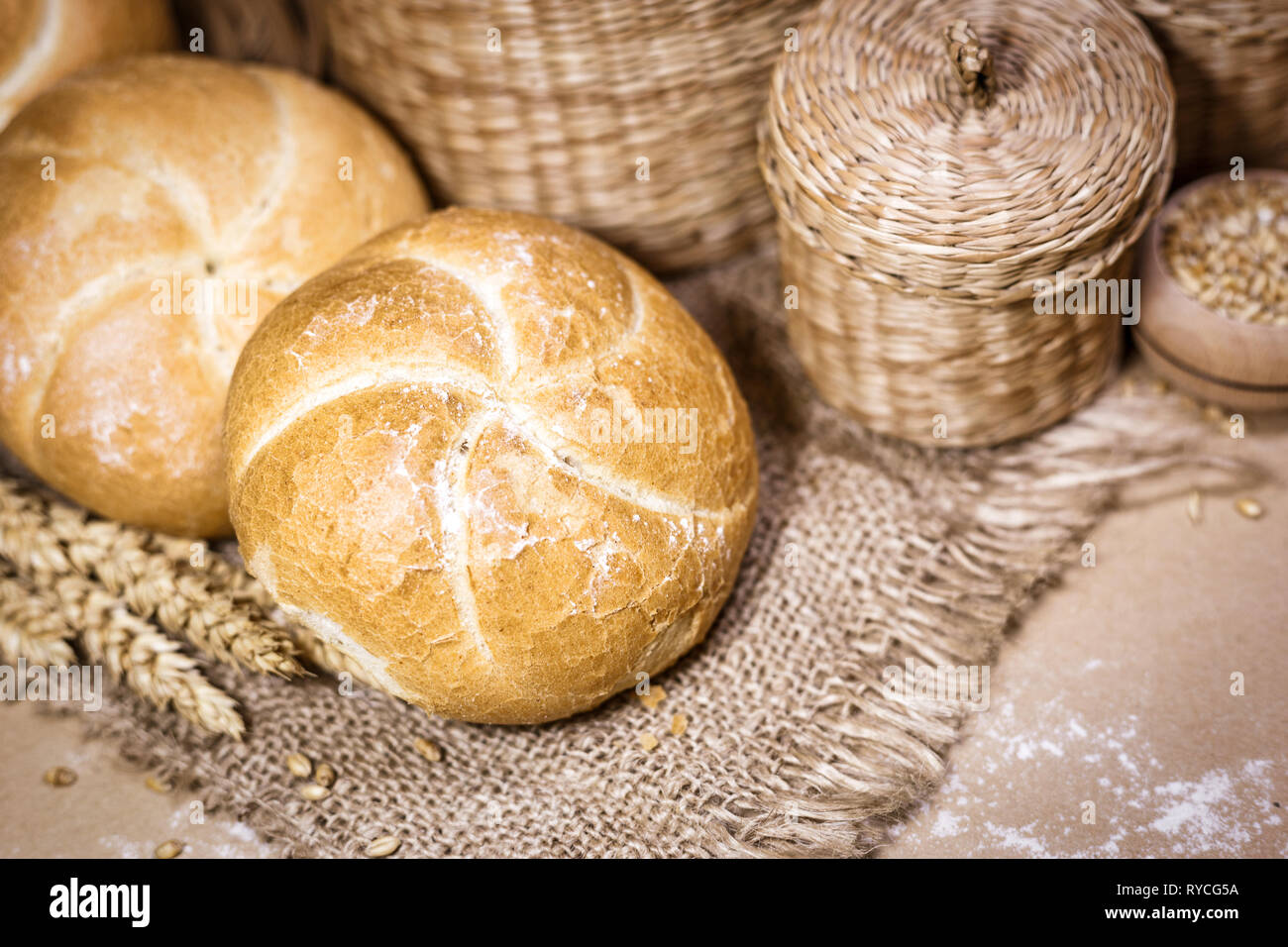 Nahaufnahme der frisch gebackene Brot auf einem urigen Hintergrund mit Weizen und Mehl. Eine Bäckerei und ein Lebensmittelgeschäft. Stockfoto