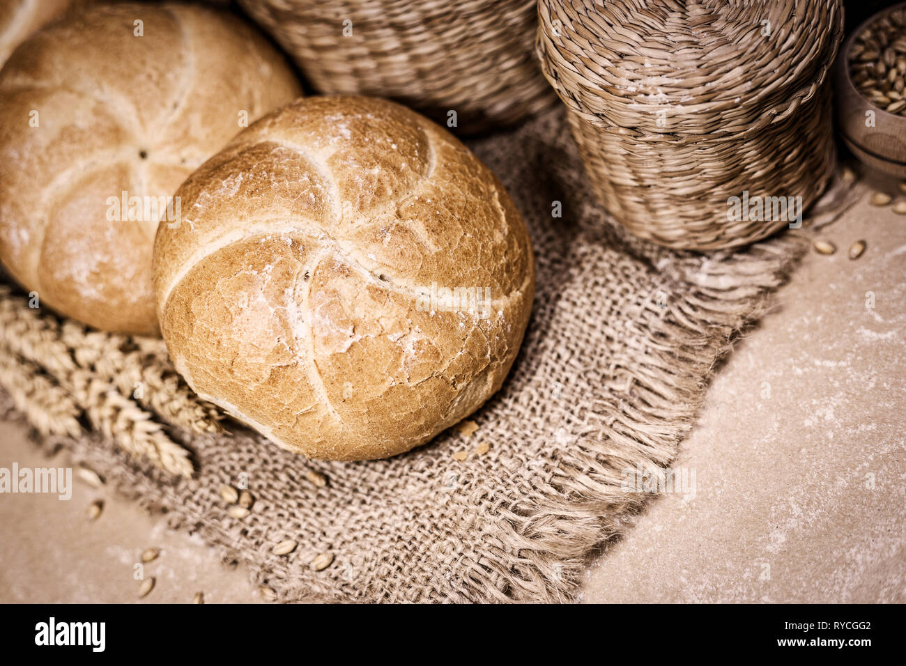 Nahaufnahme der frisch gebackene Brot auf einem urigen Hintergrund mit Weizen und Mehl. Eine Bäckerei und ein Lebensmittelgeschäft. Stockfoto