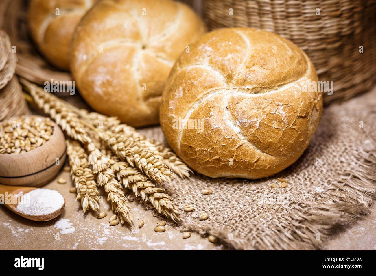 Nahaufnahme der frisch gebackene Brot auf einem urigen Hintergrund mit Weizen und Mehl. Eine Bäckerei und ein Lebensmittelgeschäft. Stockfoto