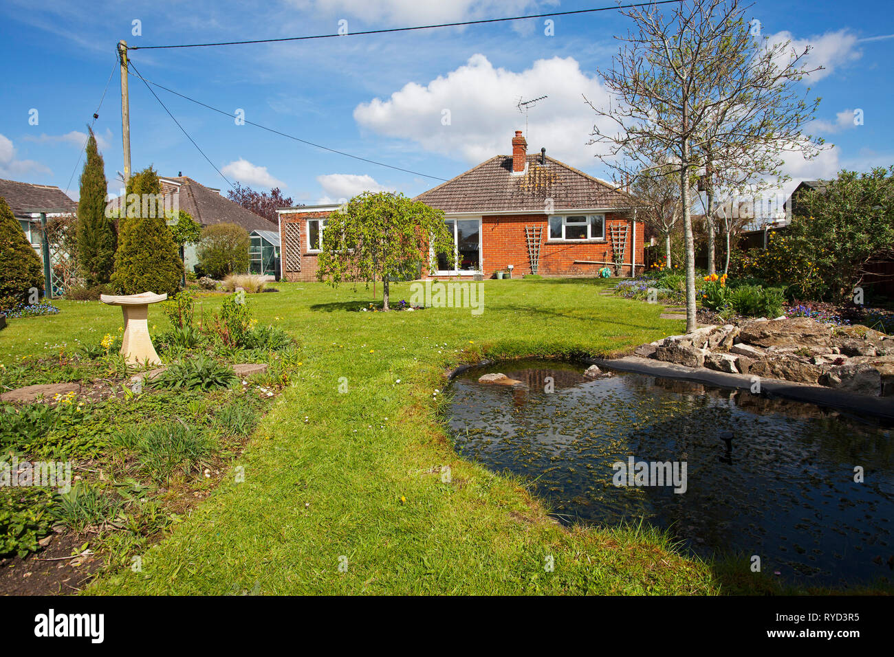 Städtische Garten mit Teich, Rasen, Bäume und Bungalow Ringwood Hampshire England UK April 2016 Stockfoto