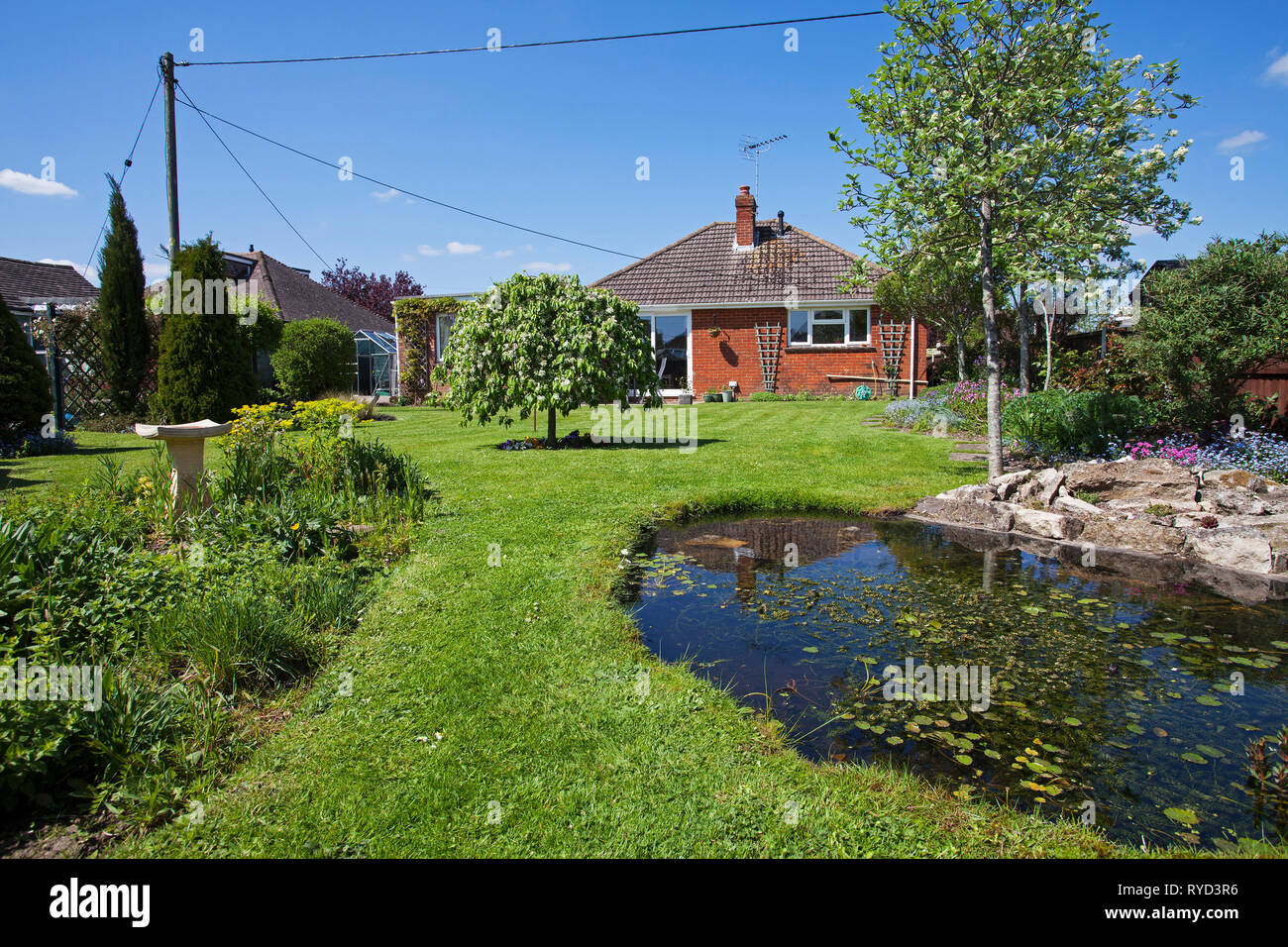 Städtische Garten mit Teich, Rasen, Bäume und Bungalow Ringwood Hampshire England UK Mai 2016 Stockfoto