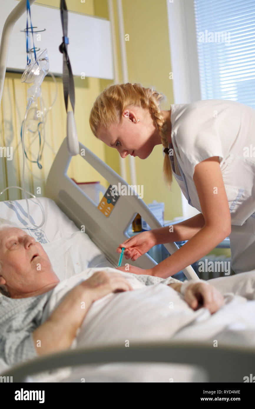 Eine Krankenschwester kümmert sich ein Patient in einem Krankenhausbett, Karlovy Vary, Tschechische Republik, Europa Stockfoto