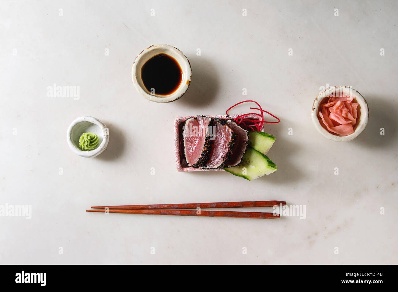 Thunfisch Sushi Sashimi mit Gurke in rosa Keramik Servierteller mit Stäbchen, Schalen mit Sojasauce, und eingelegtem Ingwer, Baumwolle Blumen über weiß Marb Stockfoto