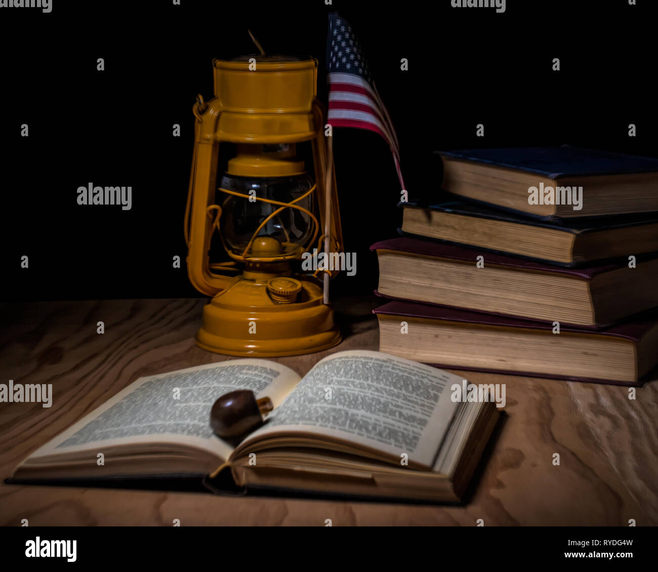 Gestapelte vintage Bücher auf einem Schreibtisch mit einem alten gelben Deutschen Lampe geschlossen, ein Rohr und eine amerikanische Flagge - Klassische litereracy Konzept Stockfoto