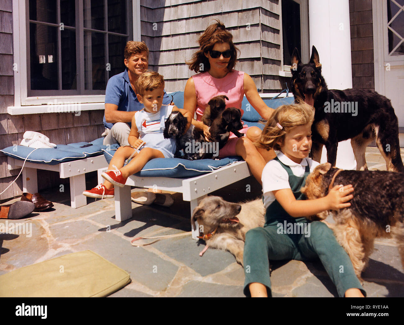 Kennedy Familie mit Hunden während einem Wochenende in Hyannisport - Hyannisport Wochenende. Präsident Kennedy, John F. Kennedy jr., Frau Kennedy, Caroline Kennedy. Hunde: Clipper (stehend), Charlie (mit Caroline), Wolf (liegend), Shannon (mit John jr.), zwei von Pushinka's Welpen (mit Frau Kennedy). August 1963 Stockfoto