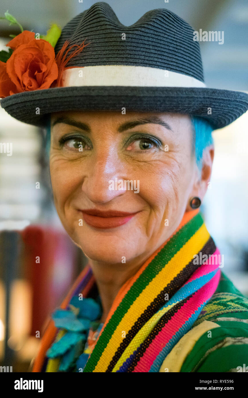 Stilvolle reife Frau in den 60er Jahren trägt einen schwarzen Hut mit einer Rose und einem bunten Schal ihre blauen Haare Akzentuierung. Stockfoto