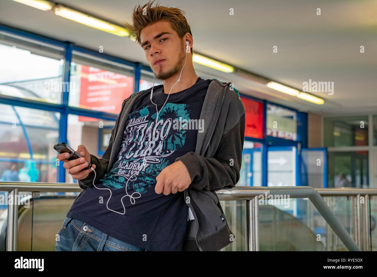 Junge cool Dude Musik auf seinem Telefon, während für einen Freund in einem U-Bahnhof in der Innenstadt von Warschau, Polen warten Stockfoto
