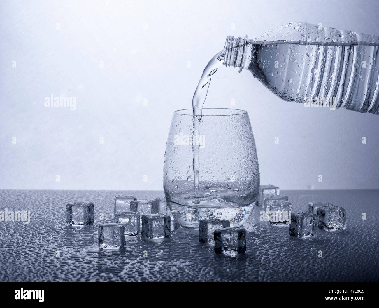 Gießen frisches Trinkwasser Mineralwasser aus Plastikflaschen. Glas mit Wasser auf weißem Hintergrund gefüllt. Stockfoto