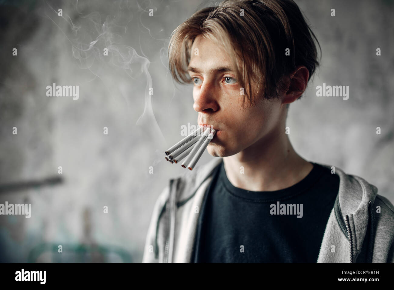 Junge Junkie mit vielen Zigaretten in den Mund Stockfoto