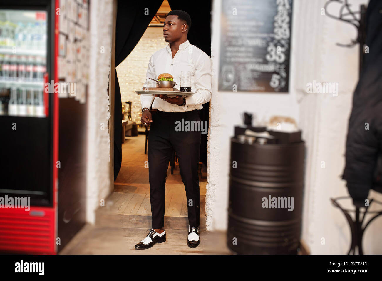 Junge afrikanische amerikanische Kellner mann Fach mit Burger Restaurant. Stockfoto