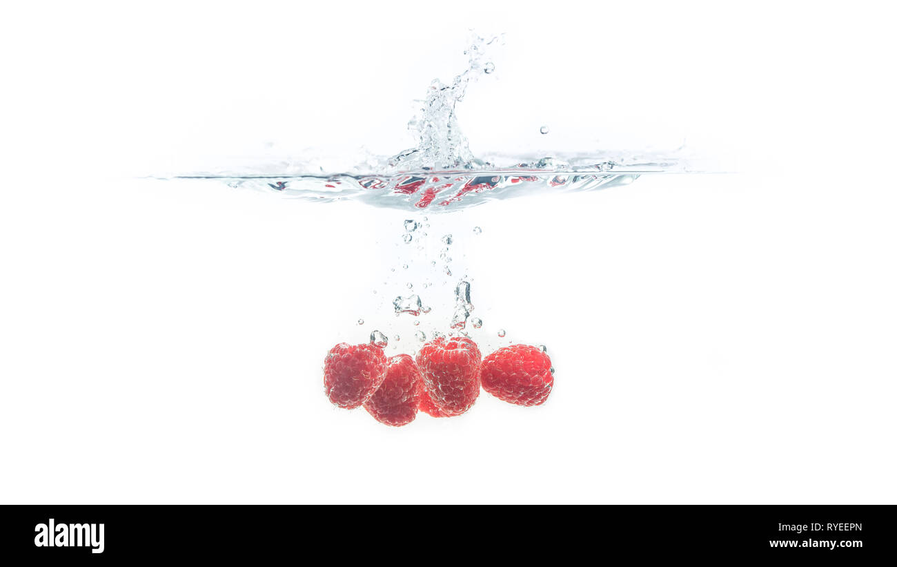 Bündel von saftig lecker aussehenden Himbeeren Spritzer in die Wasseroberfläche und Untergang. Auf weißem Hintergrund, Splash essen Fotografie. Stockfoto