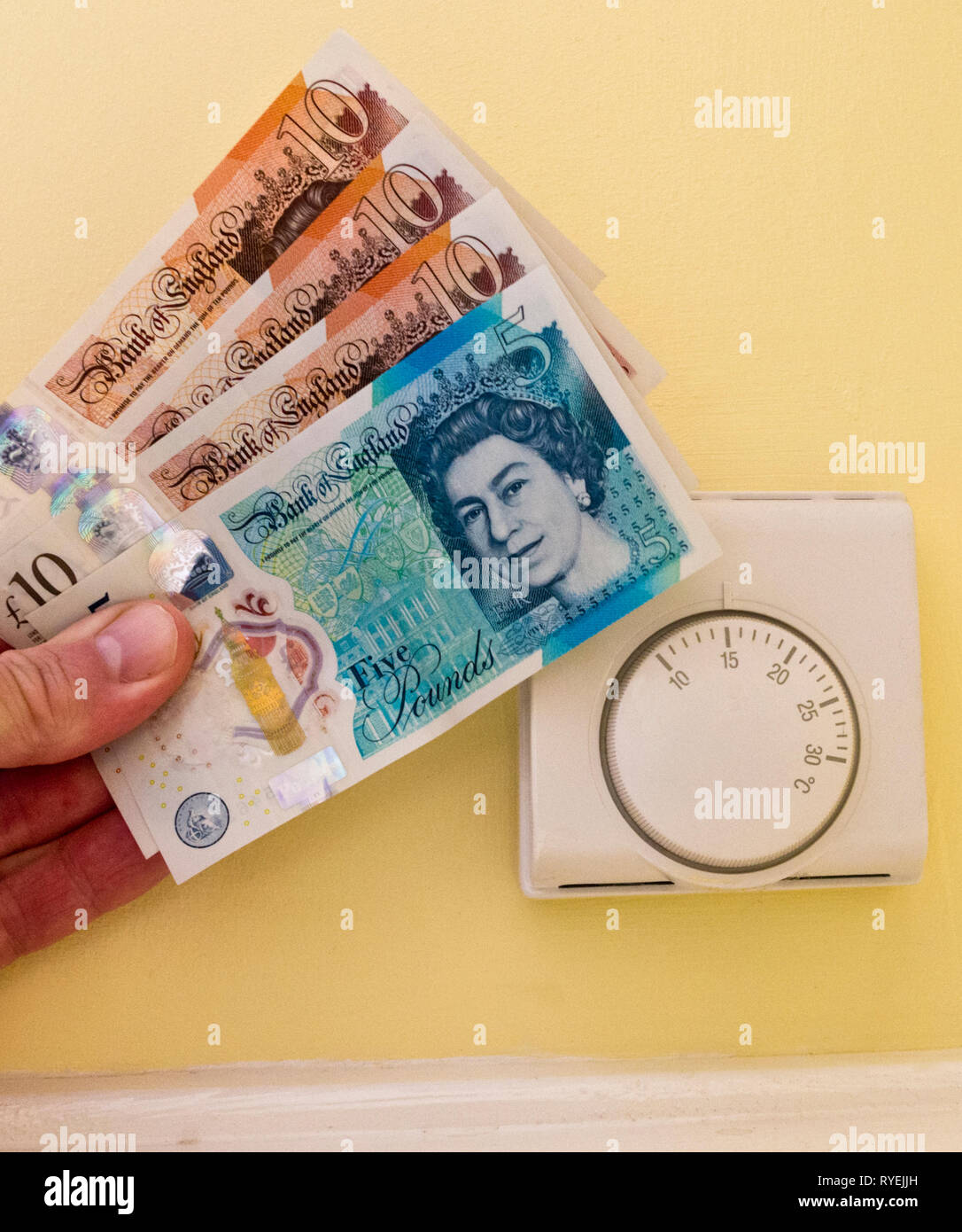Honeywell Zentralheizung Raumthermostat mit des Menschen Hand Pfundnoten Geld für Heizkosten, Großbritannien Stockfoto