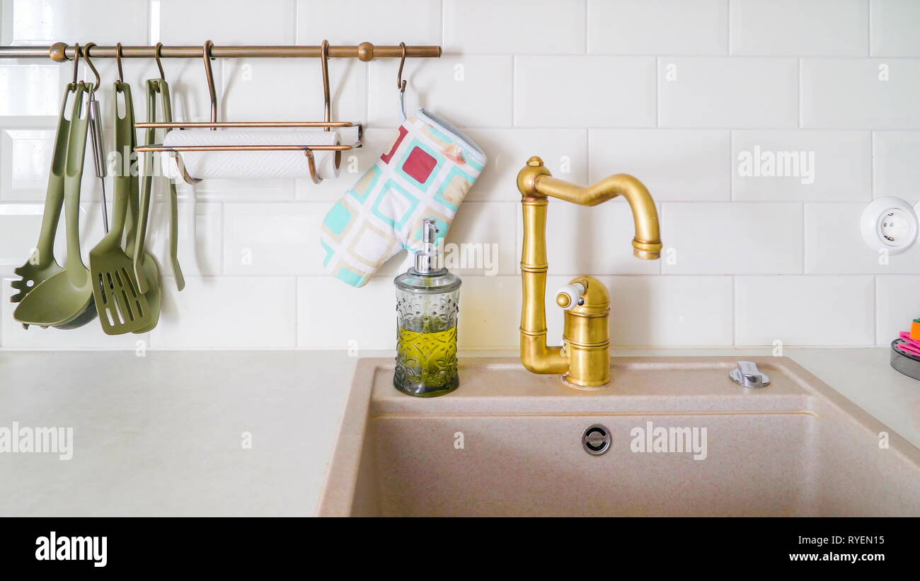 Der goldene Hahn von der Spüle in der Küche mit dem Geschirr und den Pot  Halter an der Wand hängen Stockfotografie - Alamy