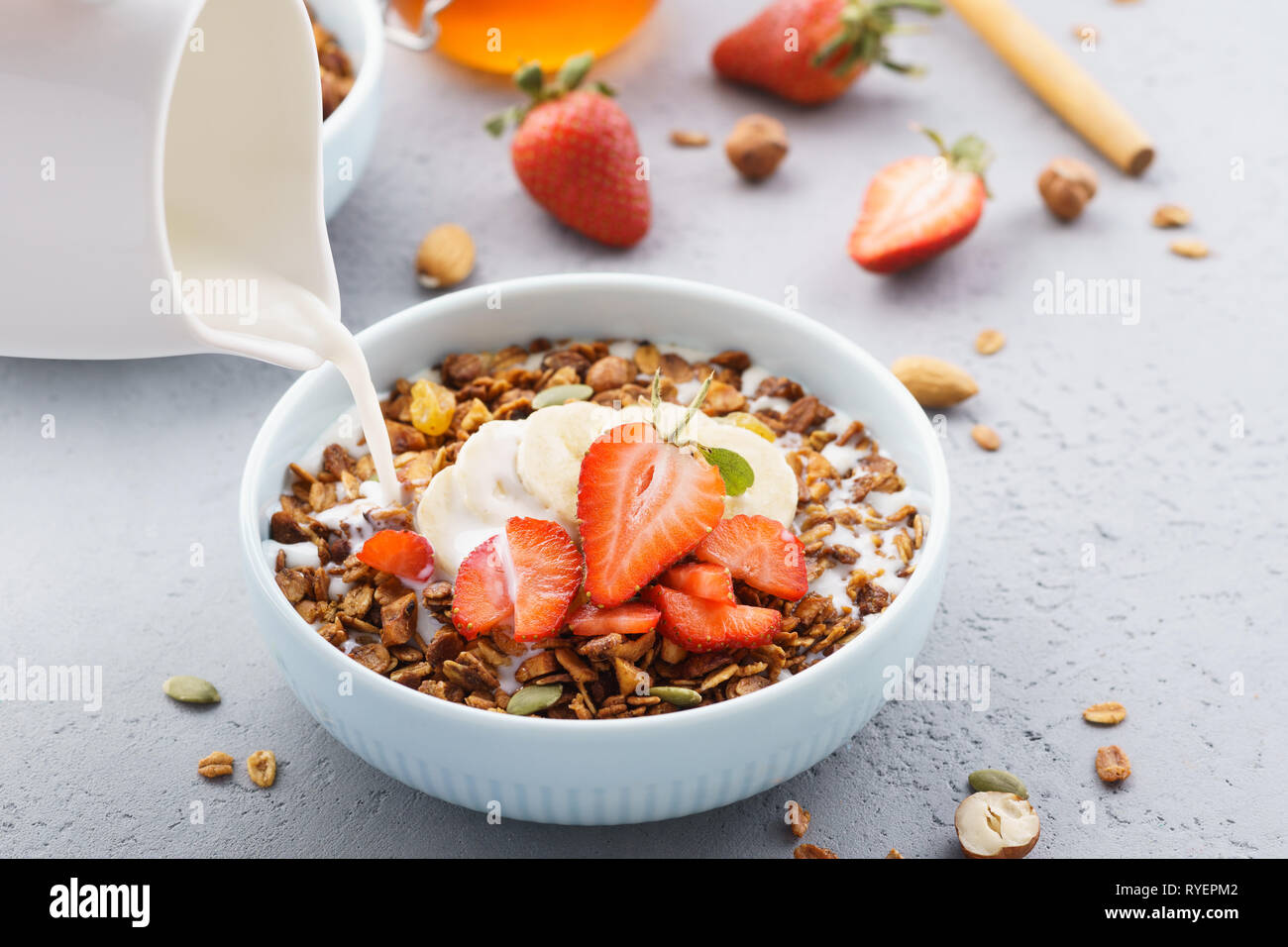 Gieen Milch in eine Schssel Msli. Mit Erdbeer und Banane serviert  Stockfotografie - Alamy