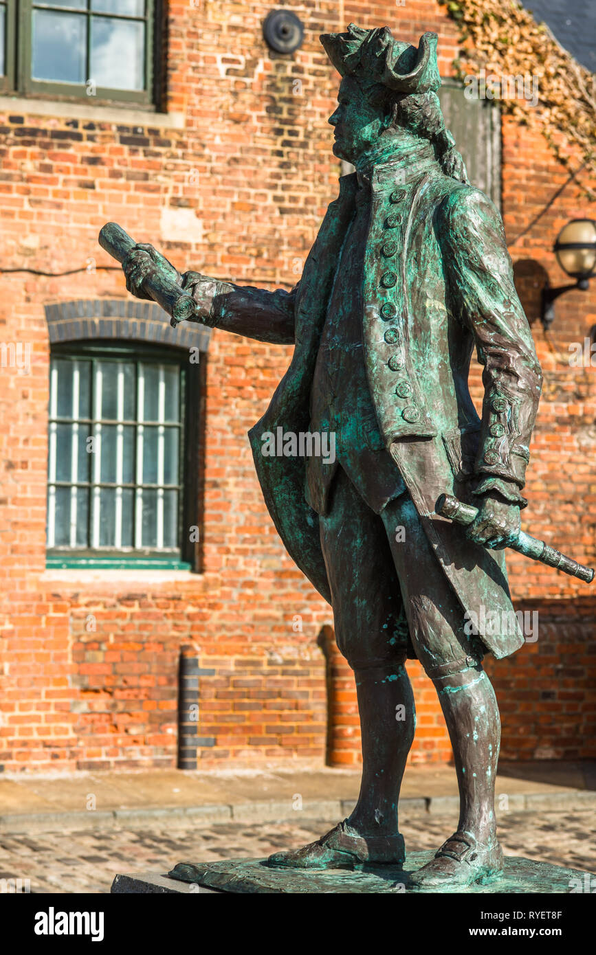 Statue von Captain George Vancouver vor dem Hintergrund einer alten Lagerhalle, Purfleet Quay, King's Lynn, Norfolk, England, UK. Stockfoto