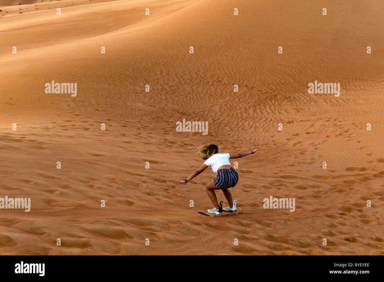 Junge Mädchen Sandboarding in der Wüste - extreme Wüste in Dubai Stockfoto