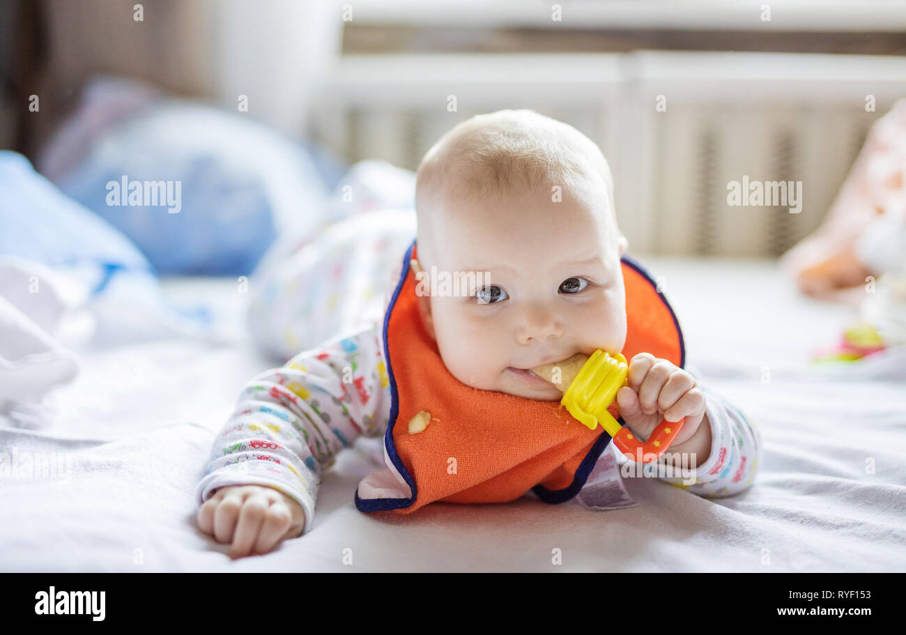 Süße kleine Baby das Essen von Früchten in Nager auf dem Bett zu Hause. Stockfoto
