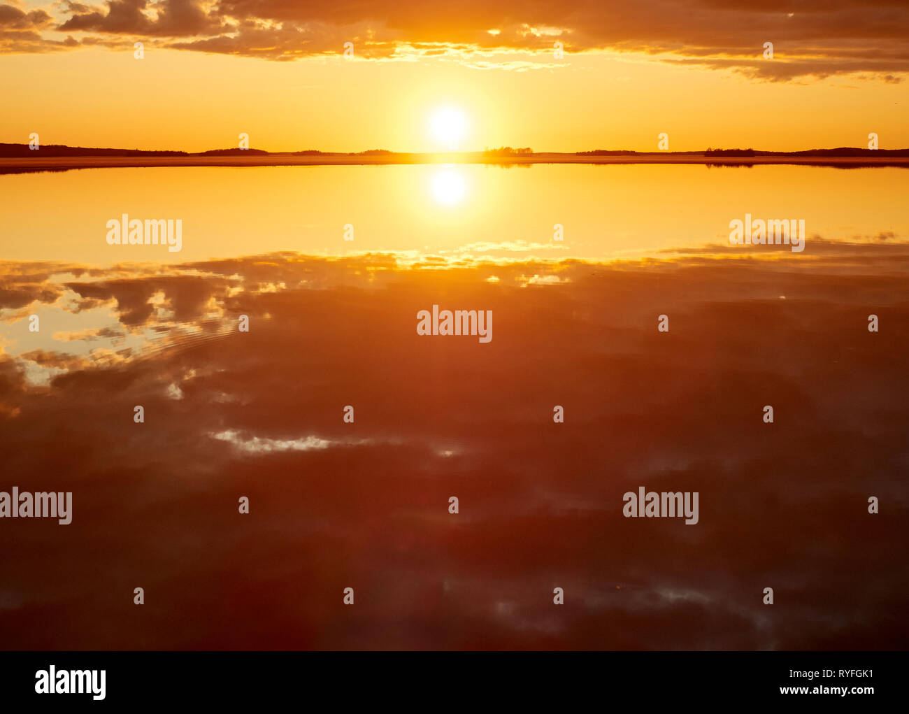 Idyllischen Sonnenuntergang mit Wolken im Sommer. Dramatische Reflexion der Sonne im Wasser eines Sees in Finnland. Stockfoto