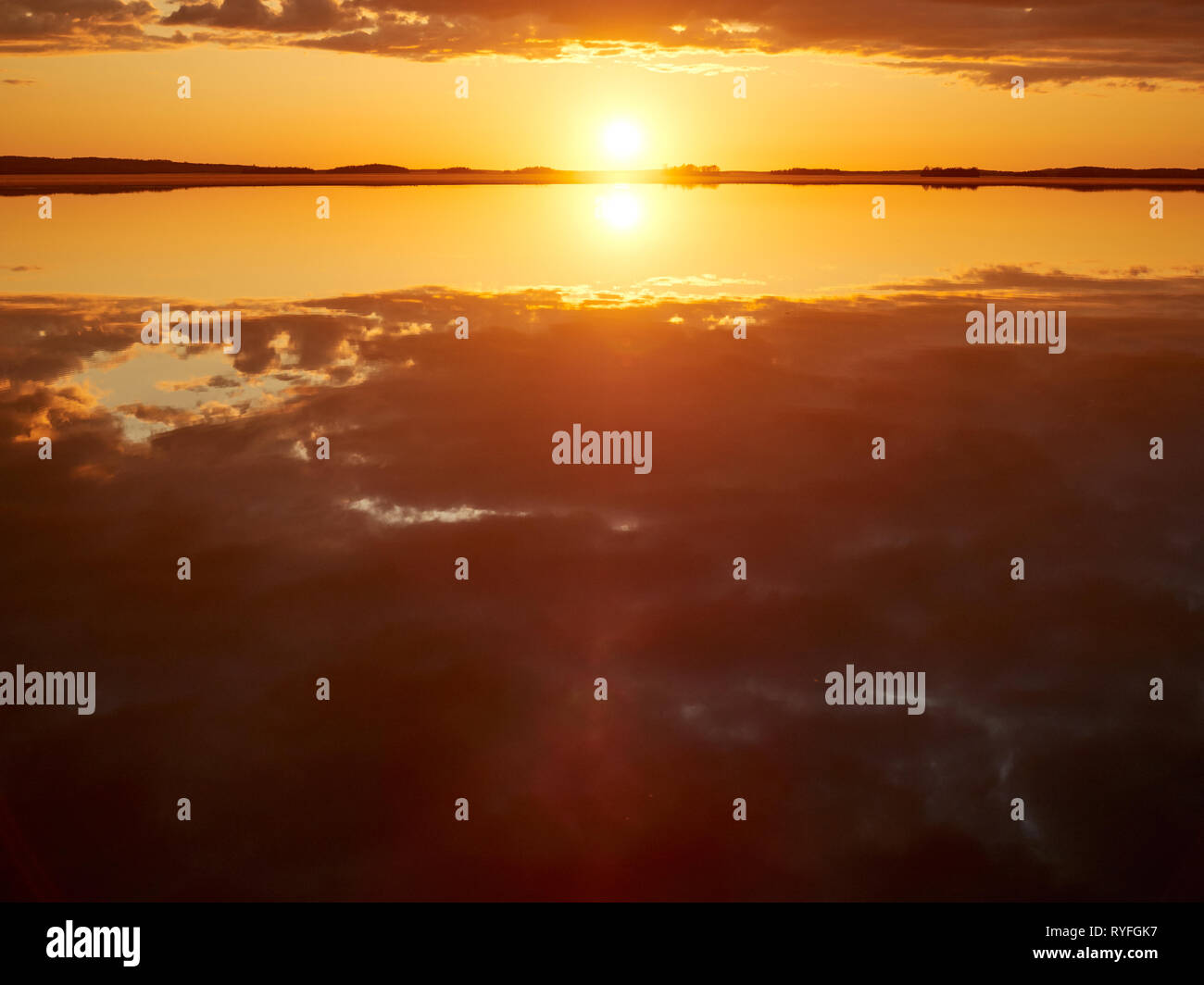 Idyllischen Sonnenuntergang mit Wolken im Sommer. Dramatische Reflexion der Sonne im Wasser eines Sees in Finnland. Stockfoto