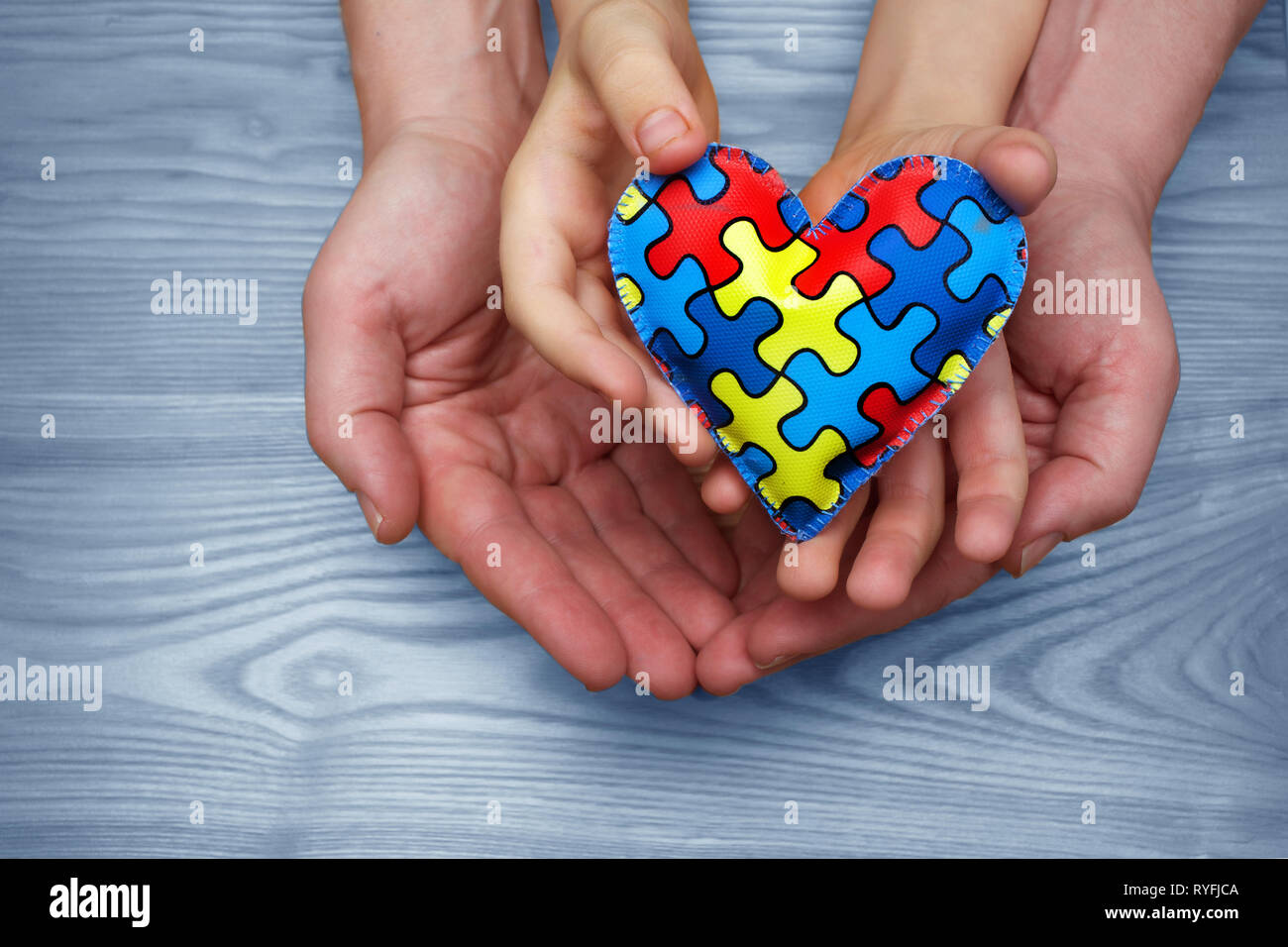 Welt Autismus Bewußtsein Tag, Puzzle oder Stichsäge Muster auf Herz mit autistischen Kind und Vater Hände Stockfoto