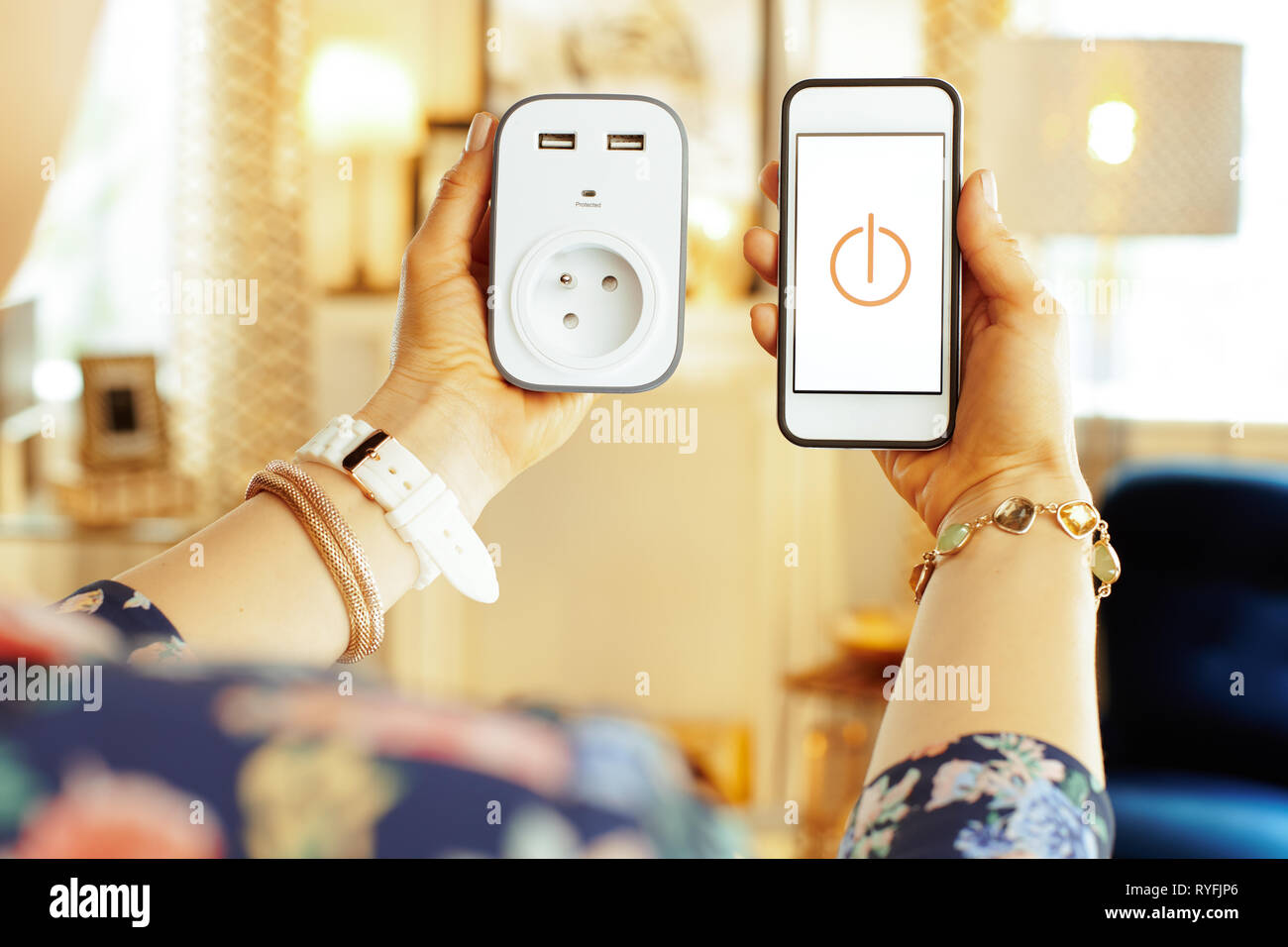 Nahaufnahme auf Smartphone mit smart home App und wifi Smart Plug in der Hand der modernen Hausfrau im Haus. Stockfoto