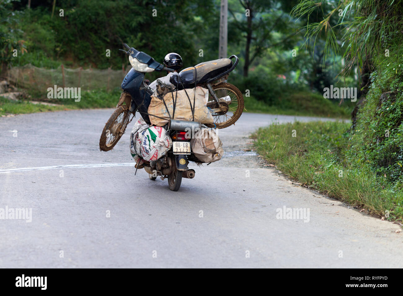 Mann, der einen Roller auf einem Motorrad in SaPa. Vietnamesische Volk werden verwendet, um zu laden und zu transportieren, eine Menge Sachen auf dem Motorrad. Vietnam Stockfoto
