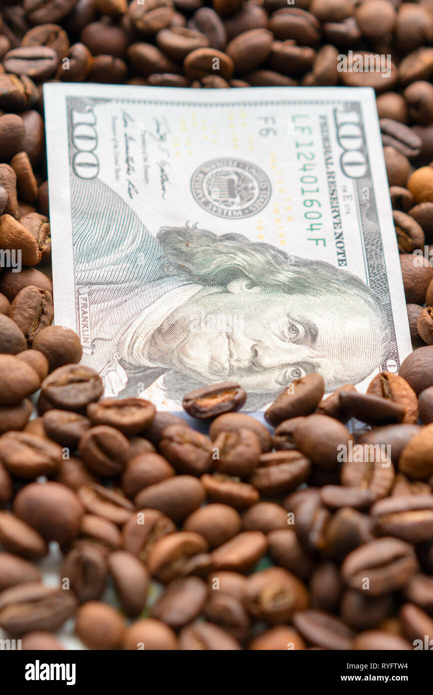 Banknote von 100 US-Dollar, zwischen Körner von Kaffee. Business Konzept für den Kauf, den Verkauf, die Lieferung und den Vertrieb von Kaffee. Stockfoto Banknote von 100 US-Dollar, zwischen Körner von Kaffee. Business Konzept für den Kauf, den Verkauf, die Lieferung und den Vertrieb von Kaffee. Stockfoto