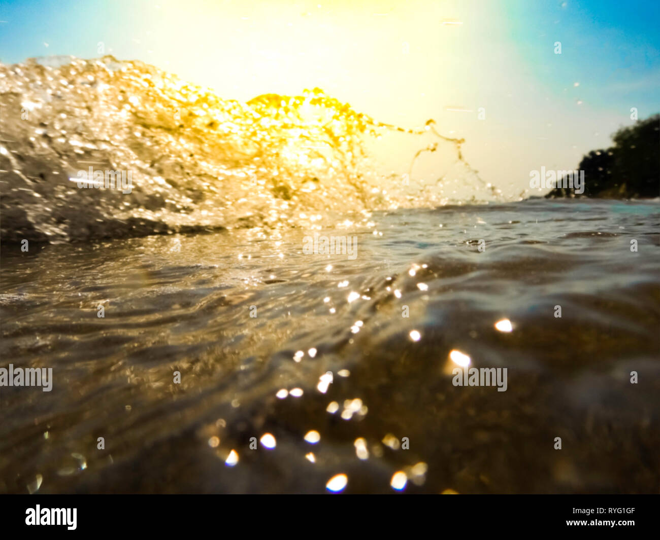 Verschwommen Ocean Wave gegen direkte Sonne - Außerhalb des Fokus sea wave Quetschungen am Strand unter direkter Sonneneinstrahlung - Salzwasser am Sandstrand Stockfoto
