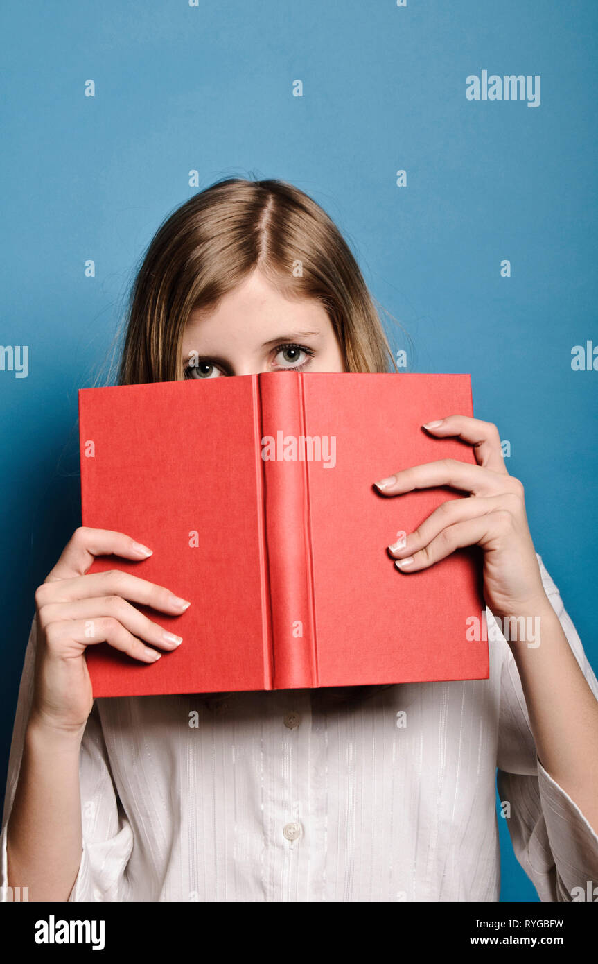 Blonde Mädchen hinter einem roten Buch ausblenden Stockfoto