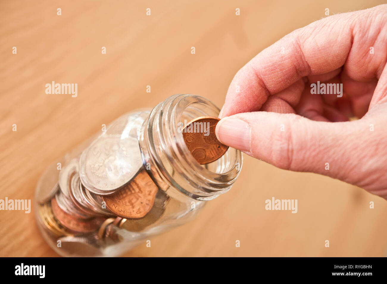 Hand eine Münze in eine Einsparung jar Stockfoto