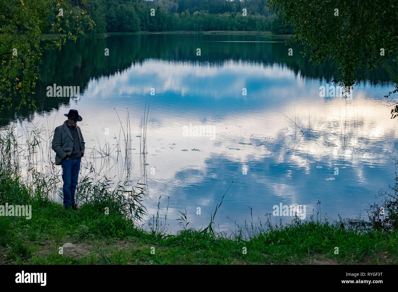 Mann in Hut ab, als er von der Seite des Wassers in der Nähe von Sunset steht im Seengebiet von Nordosten Polens in der Nähe von Suwalki Stockfoto