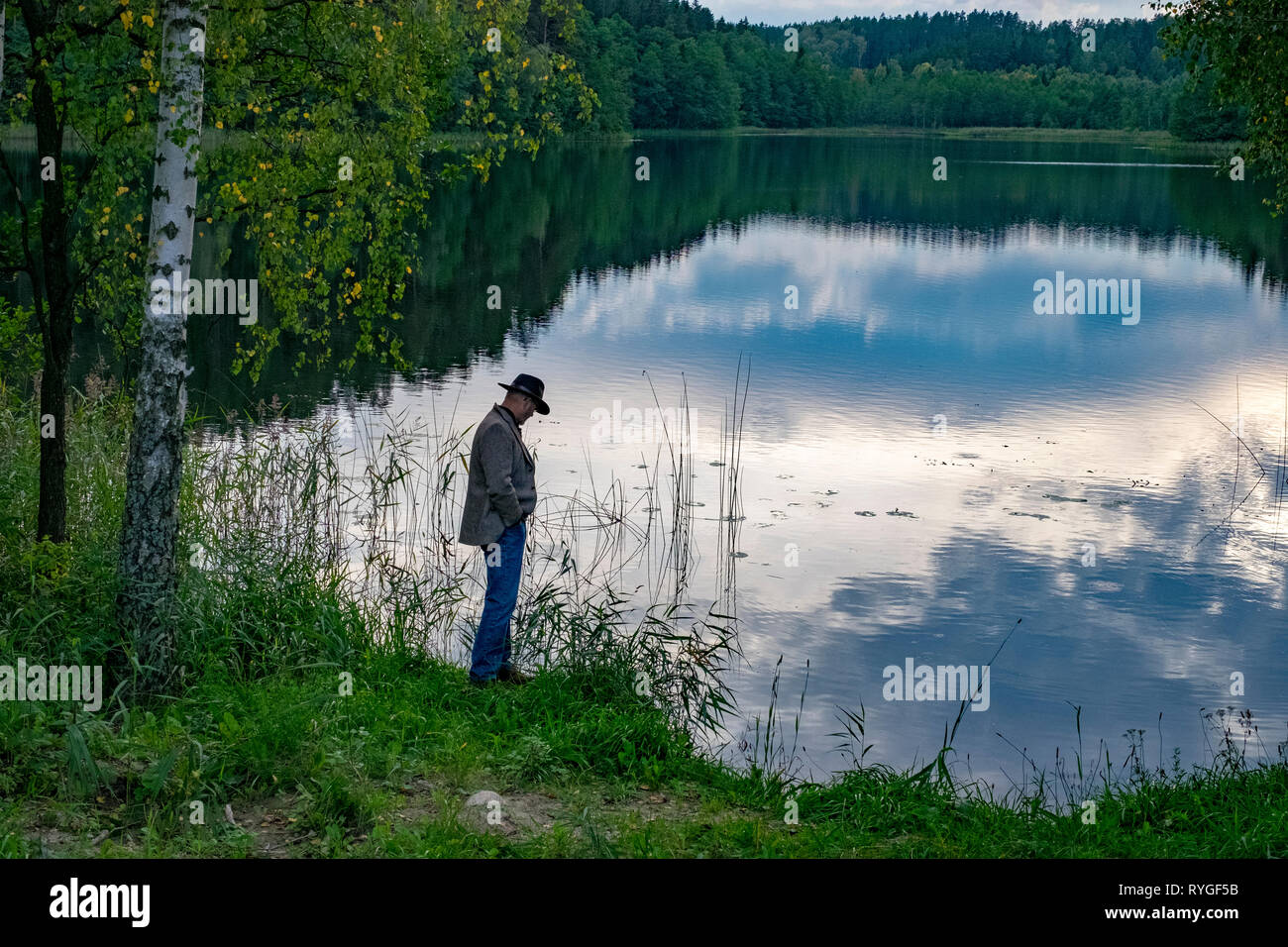 Mann in Hut ab, als er von der Seite des Wassers in der Nähe von Sunset steht im Seengebiet von Nordosten Polens in der Nähe von Suwalki Stockfoto